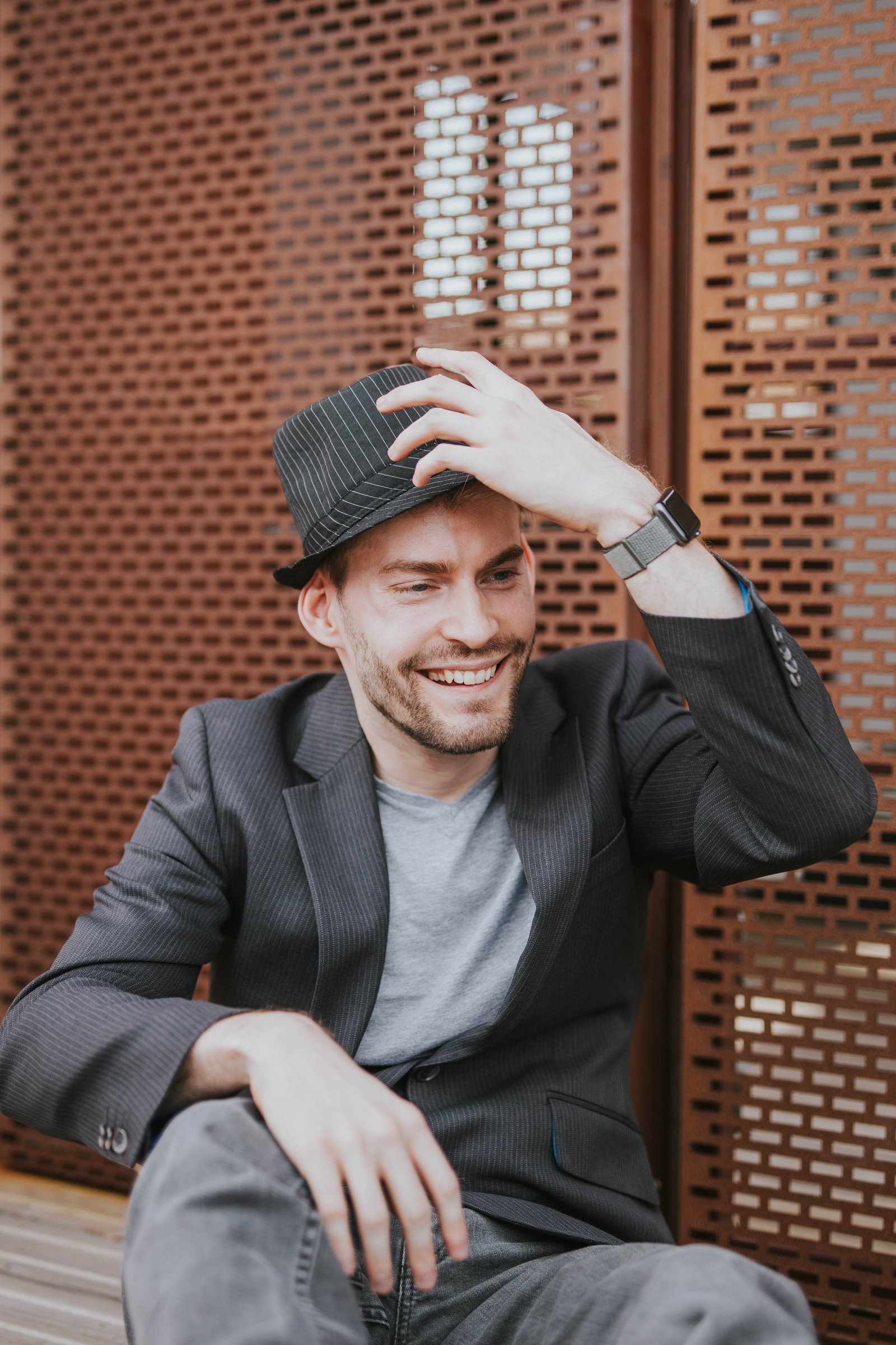 A picture of Dan wearing a suit jacket and trilby hat smiling
